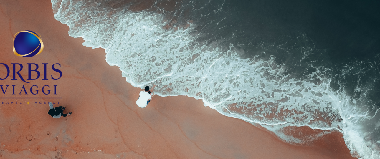 Immagine suggestiva di una coppia sulla riva del mare al tramonto, simbolo di esperienze autentiche e viaggi su misura con Orbis Viaggi, agenzia a Rimini.